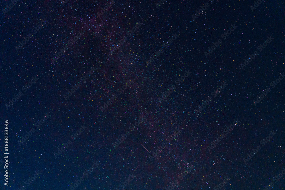 Obraz premium Photograph of the night sky with fragment of the Milky Way galaxy with falling meteorite and purple glow. Astronomy as science: study of celestial bodies, stars, meteors, asteroids and other objects