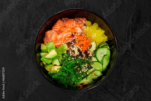 Delicious hawaiian salmon poke bowl with avocado and cucumber on dark background