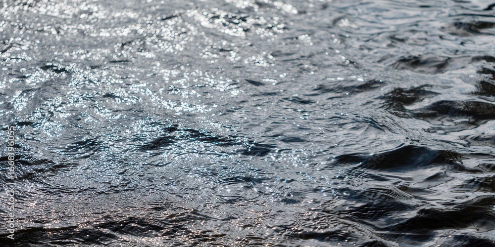 Obraz premium Dark water surface with gentle waves and reflections, a tranquil scene.