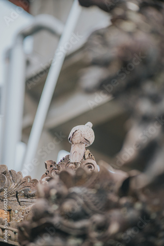Light Brownish Dove Resting on an Ornate Stone Sculpture In a Temple In Bali, Indonesia