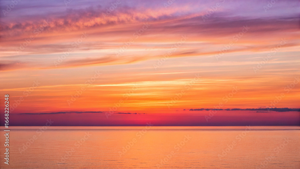 Fototapeta premium Fiery sunset over a calm ocean with vibrant orange and purple sky water