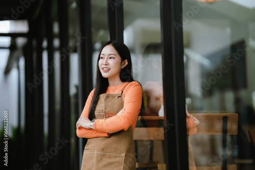 Smiling female barista in apron standing at café entrance, giving thumbs up, welcoming customers with joy and confidence. Free Download Smiling female barista in apron standing at café entrance, giving thumbs up, welcoming customers with joy and confidence. - GFXLoad