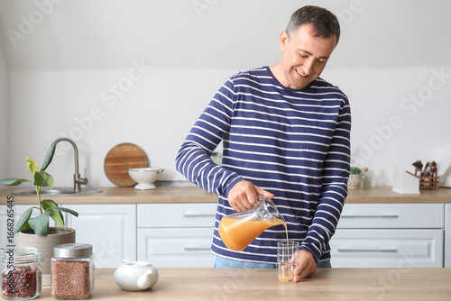 Mature man pouring orange j...