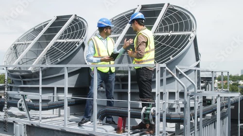 Architects reviewing blueprints on rooftop HVAC system