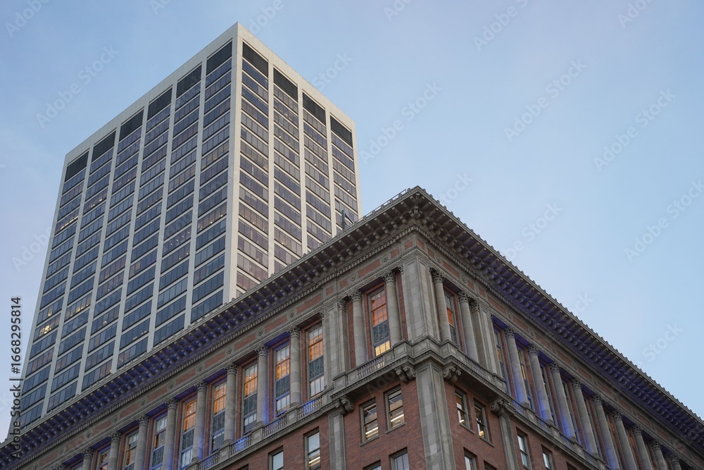 Fototapeta premium Modern skyscraper and historic building in urban setting.