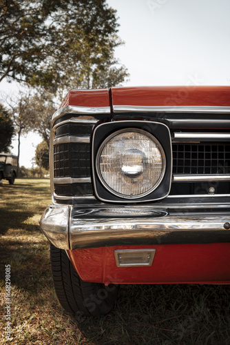 Fotografía Front view of a red classic car, highlighting the single headlight, metallic frame, and chrome bumper finish