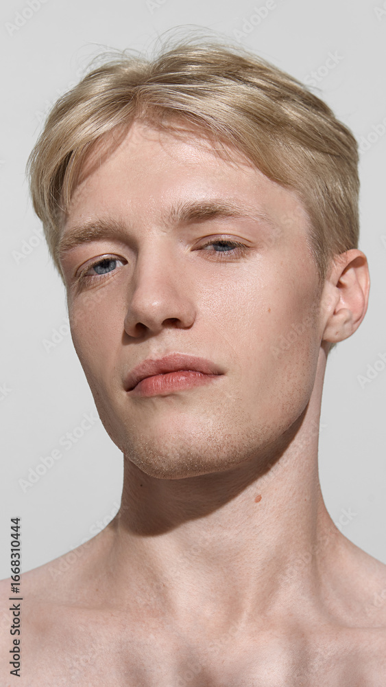Obraz premium Portrait young man looking straight neutral expression. Concept of beauty editorial, grooming campaign, wellness platform, lifestyle branding, cosmetic design, and men mental health awareness.