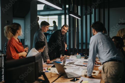 Obraz na płótnie A diverse group of business colleagues gather around a table in a modern office, engaged in a lively brainstorming session