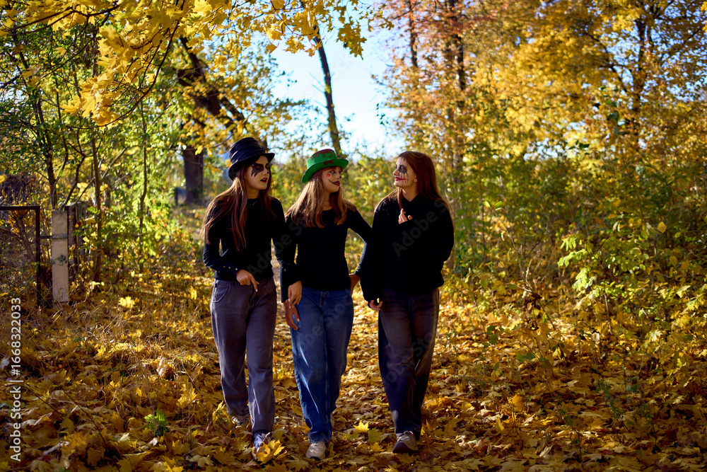 Naklejka premium Teenage friends with stage makeup of a mime during an acting lesson celebrate Halloween in the park near the school, act out scenes and have fun