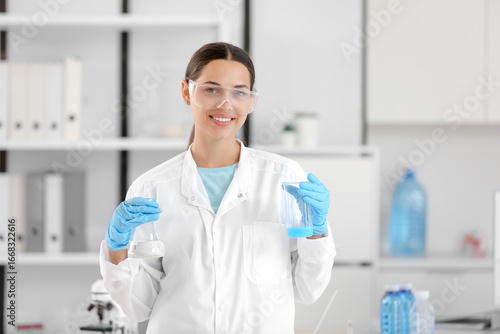 Happy female young scientist with flasks of water samples in research laboratory