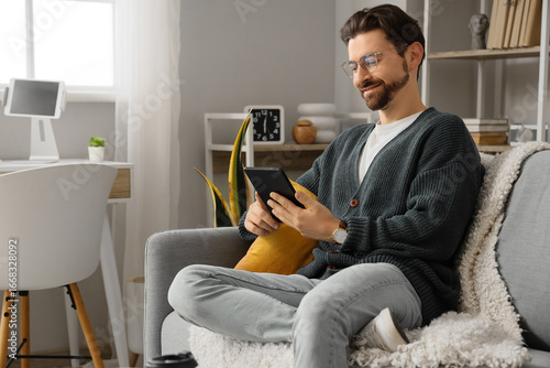 Young man with e-reader sit...