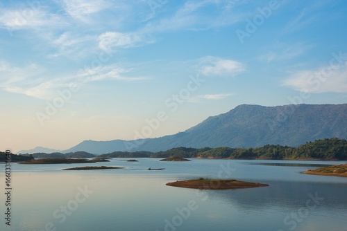 Peaceful Fisherboat on Nam Ngum Reservoir Surrounded by Mountains near Vang Vieng, Laos at Sunrise