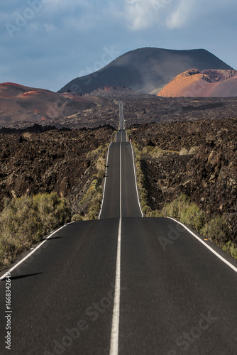 Long empty road crossing volcanic landscape in lanzarote, canary islands