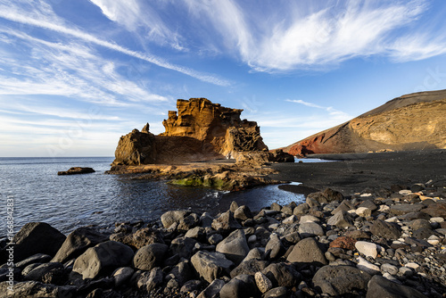 Eroded rock formation overlooking volcanic black sand beach in el golfo, lanzarote, canary islands, spain