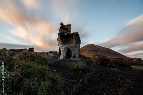 Roque partido emerging from the volcanic landscape at sunset in fuerteventura, canary islands