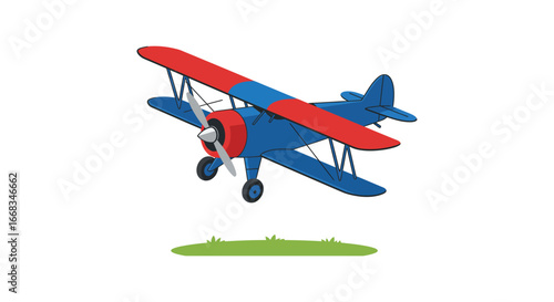 A blue and red vintage biplane flying over a small patch of grass