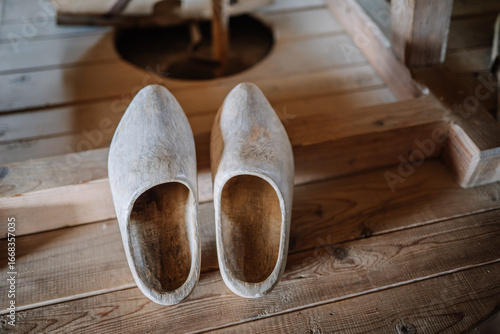 Fototapeta A close-up of a pair of traditional wooden clogs placed on rustic wooden floorboards, likely in a historical or cultural setting