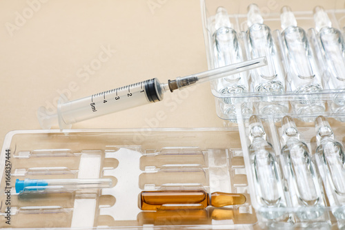 Tableau sur toile Medical ampoules filled with liquid solution placed alongside a plastic syringe and sterile needle on a clean white background