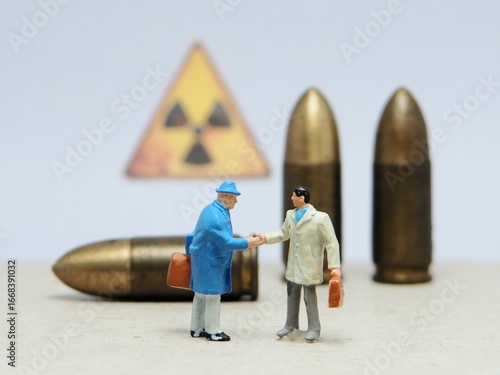 Mini toy of action figure at bullet missile with blurred background. Miniature diorama photography concept design. Minifigure of leader handshake with other people with balistic rudal weapon.