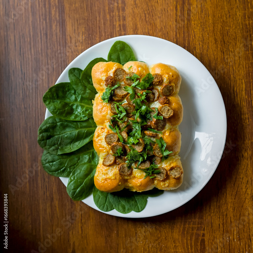 Top Down Shot of Cumberland Sliced Sausages with Garlic and Cheddar Cheese Dough Balls Tear and Share Bread, Spinach and Parsley