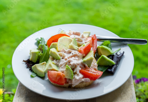 Close-up of Surimi Pollock and Prawns Tangy Seafood Sauce Salad on Toast with Avocado and Tomato, Green Outdoor Garden