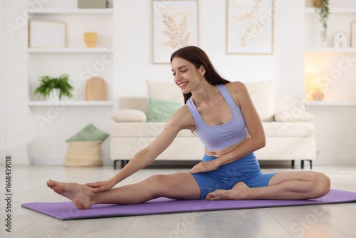 Smiling woman in sportswear stretching on mat at home Free Download Smiling woman in sportswear stretching on mat at home - GFXLoad