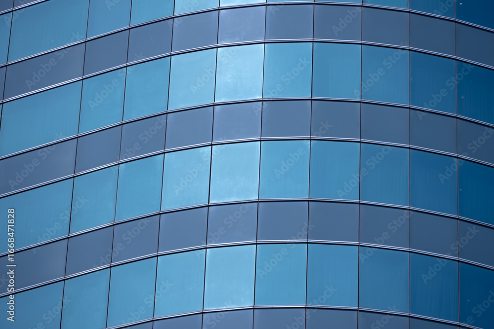 Obraz premium A section of a modern building with many rectangular glass windows reflecting the clear