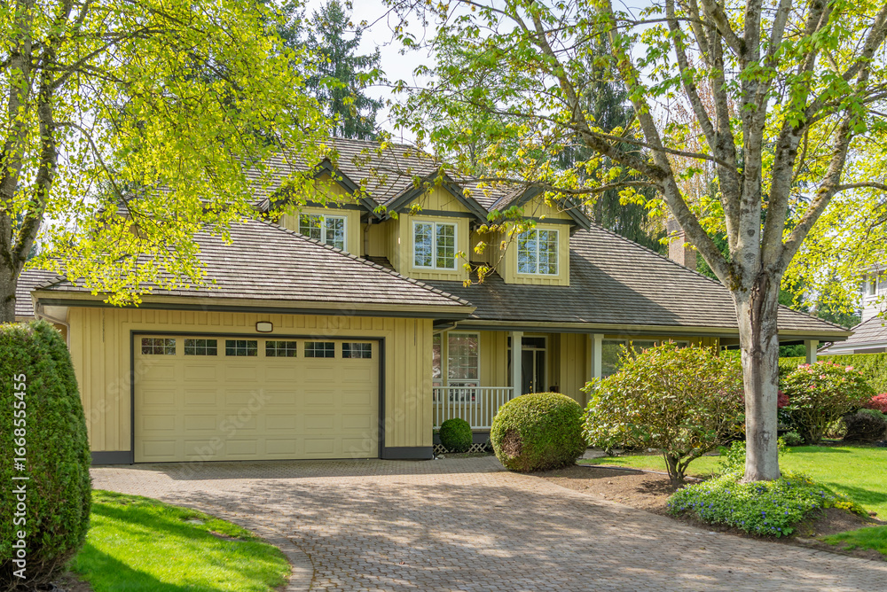 Fototapeta premium Two story stucco luxury house with nice spring blossom landscape in Vancouver, Canada, North America. Day time on May 2025.