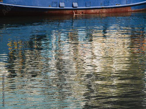 Reflections on calm water showcasing a vibrant dockside setting during a sunny afternoon