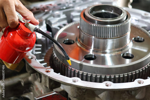 Vászonkép A mechanic's hand uses a red oil can to lubricate clutch plate into a complex transmission assembly during a detailed engine repair or maintenance process