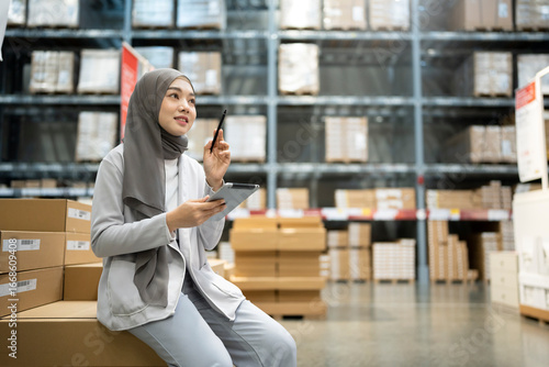 Muslim female warehouse worker holding digital tablet checking inventory in warehouse