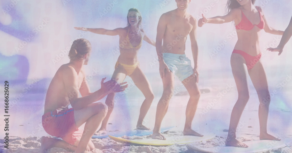 Fototapeta premium Group of six beachgoers practicing balance on surfboards on sandy beach, with bright swimwear