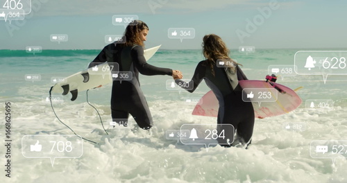 Walking wetsuit surfers carrying white and pink surfboards entering beach surf, with social icons