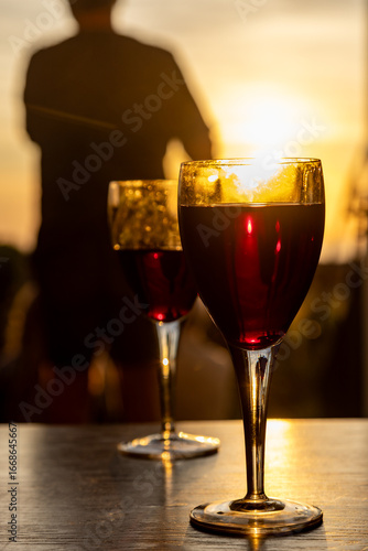 Two glasses of red wine on a table at sunset, with a shallow depth of field