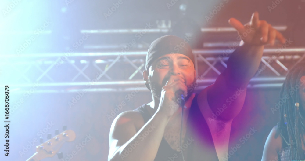 Obraz premium Gripping microphone, singer reaching out on stage under metal truss with lights and guitar neck