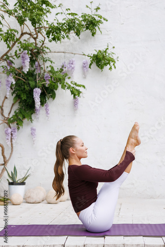 фотографія Woman doing yoga teaser outdoors against white wall with copy space