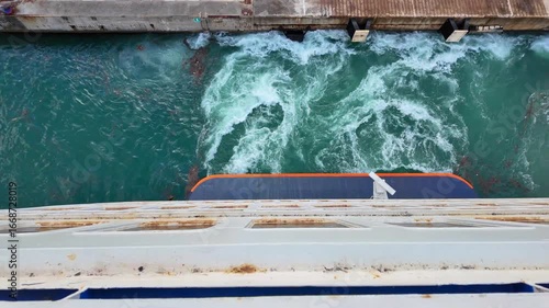 Top view from ferry as it leaves port, water swirls and turbulence in bright turquoise sea