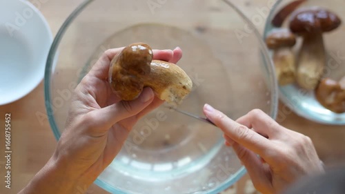 Chef is cleaning a fresh porcini mushroom with a knife over a bowl of water, preparing to cook video delicious meal a fullhd