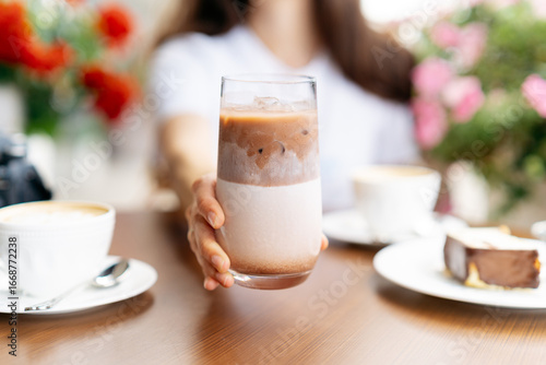 Close-up of a mid adult woman sitting at an outdoor cafe with an iced latte in summer