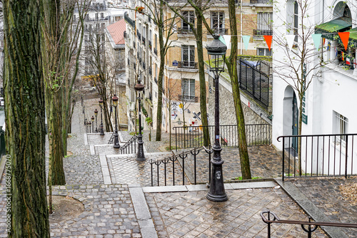 Fototapeta Naklejka Na Ścianę i Meble -  A street scene in Montmartre Paris France with a brick walkway and a row of lamp posts