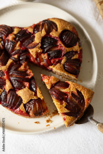 Heart-shaped plum cake with cinnamon, slice of autumn fruit homemade pastry on a white plate