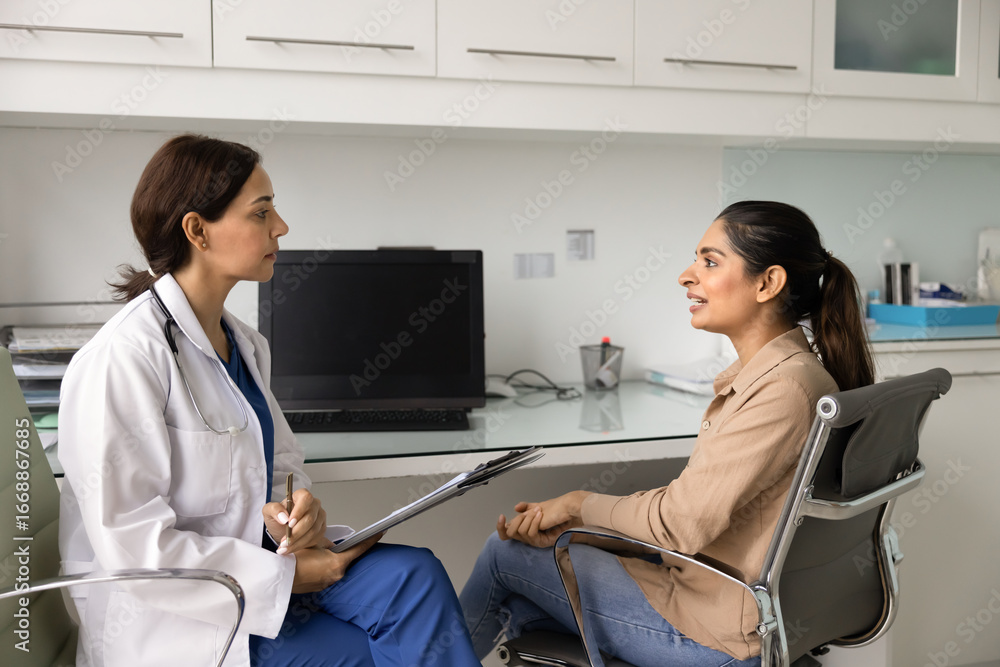 Obraz premium Diverse young physician and patient women meeting in clinic office