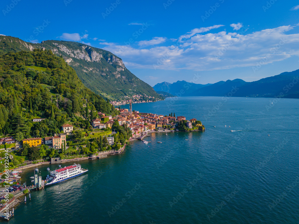 Fototapeta premium Varenna, Como lake. Picturesque village in Lombardy, Italy. Aerial panoramic drone view of beautiful town with colorful houses surrounded by mountains