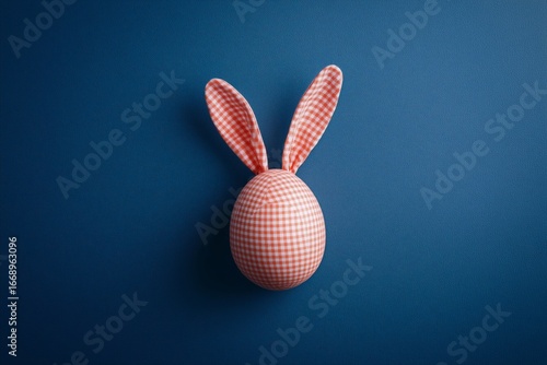 Decorative Easter Egg With Bunny Ears Displayed on a Blue Background During S...