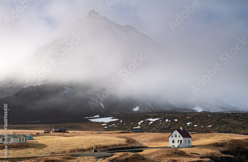 Lonely house at the small fishing village of Arnarstapi and mountain cliff covered in snow Iceland