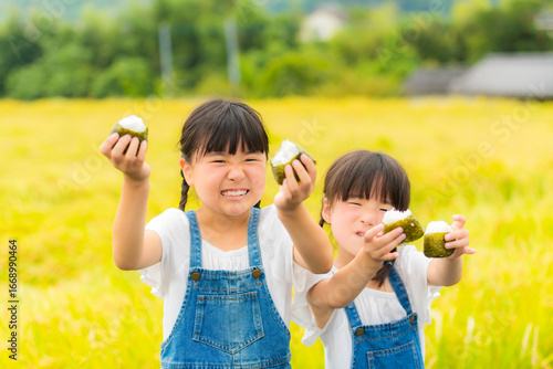 田んぼの前でおにぎりを持つ姉妹