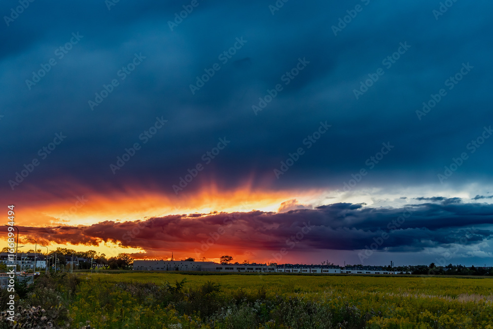 Obraz premium Dramatic sunset over field with colorful clouds