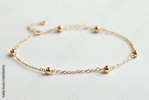 Wallpaper Mural Minimalist golden charm bracelet with small beads resting on a white background, representing elegance and simplicity in jewelry design Torontodigital.ca