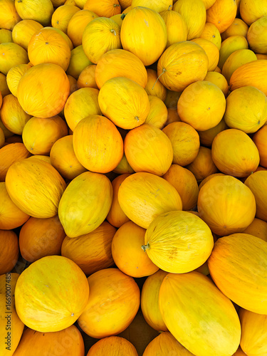 Fresh melons piled high at a local market showcasing vibrant yellow hues during the summer season