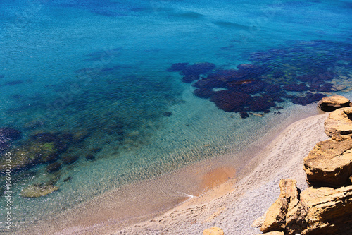 Beautiful rocky coastline with clear turquoise water and sandy beach during sunny summer day in tropical paradise